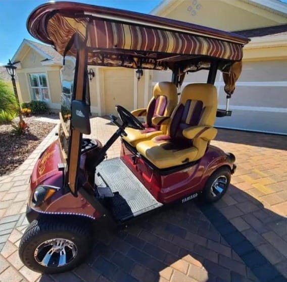 A Yamaha golf cart from David’s fleet with red bodywork and yellow seats